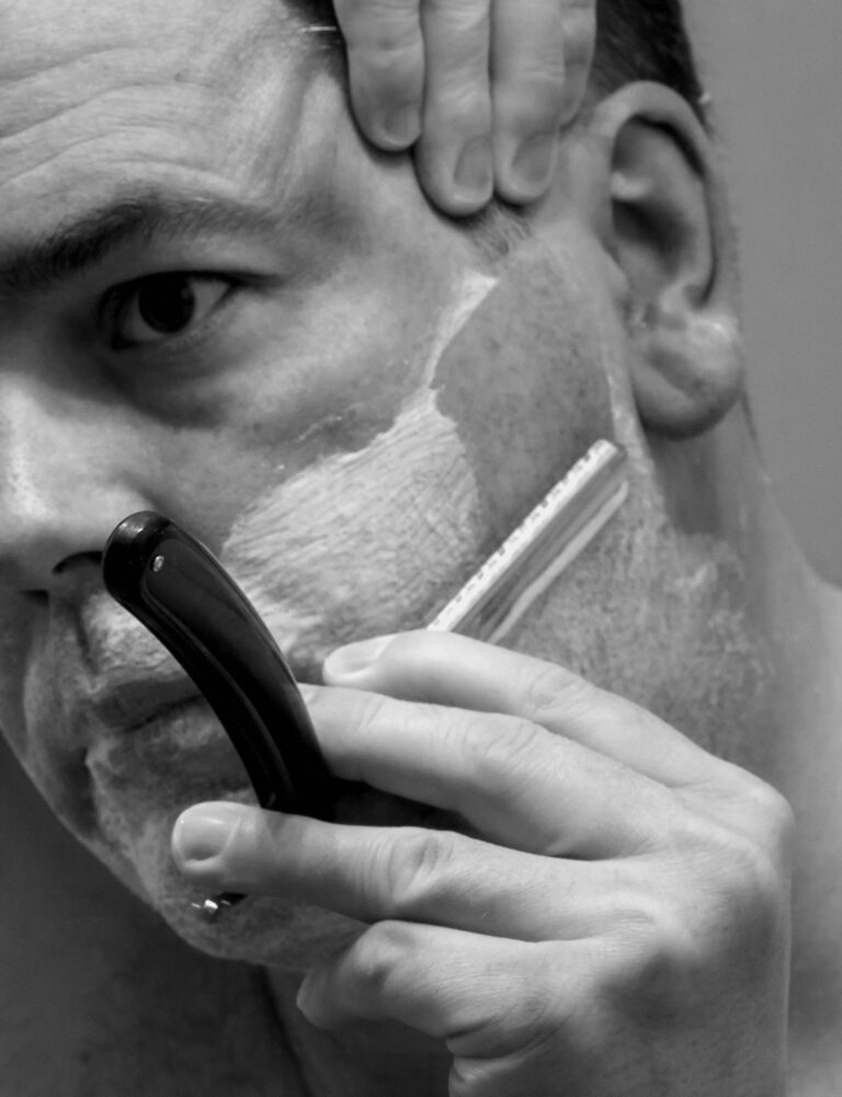 Rasage traditionnel au rasoir coupe-chou, gros plan sur la lame et la mousse